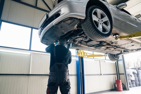 Serviceman checks car suspension on a column lift